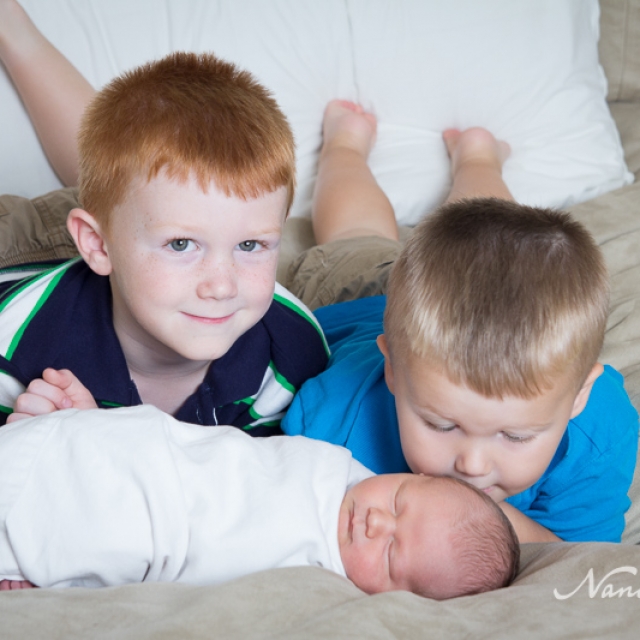 newborn with brothers on bed