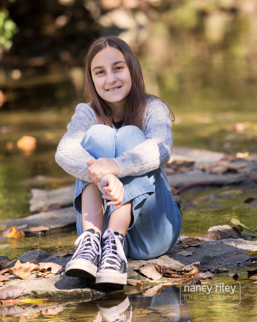 Girl hugging knees in creek Girl hugging knees in creek